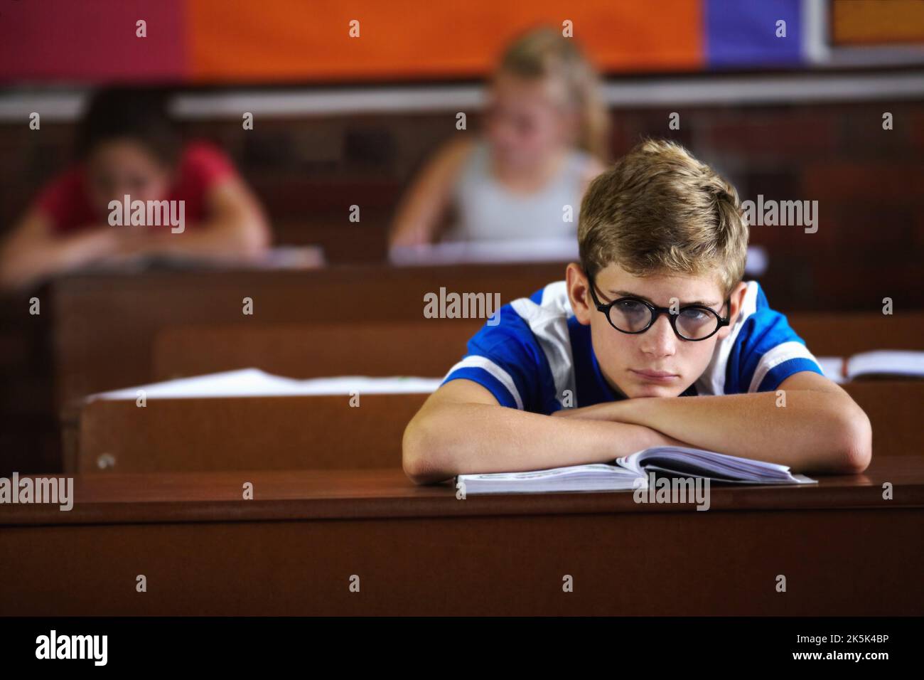 Bored of school. Young boy feeling overcome with boredom in the classroom. Stock Photo