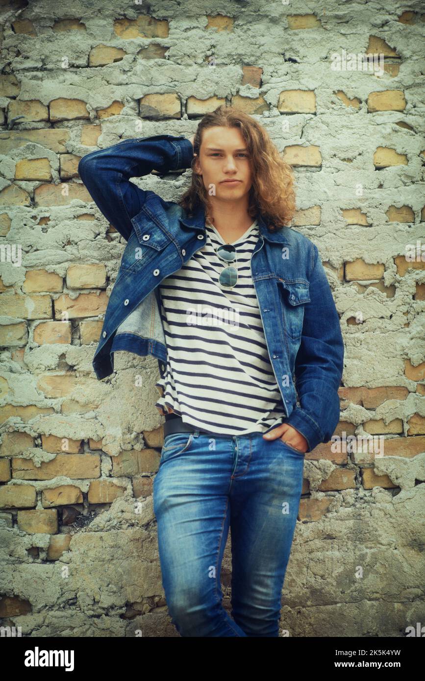 Just hanging around. Portrait of a handsome young man leaning on a brick wall. Stock Photo