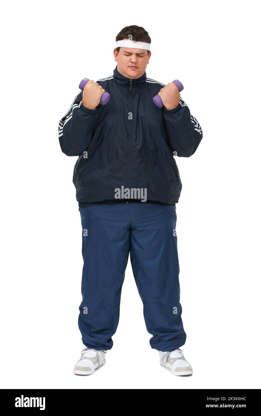 Could these be any heavier. A full length studio shot of a young obese man lifting weights and wearing a track suit. Stock Photo