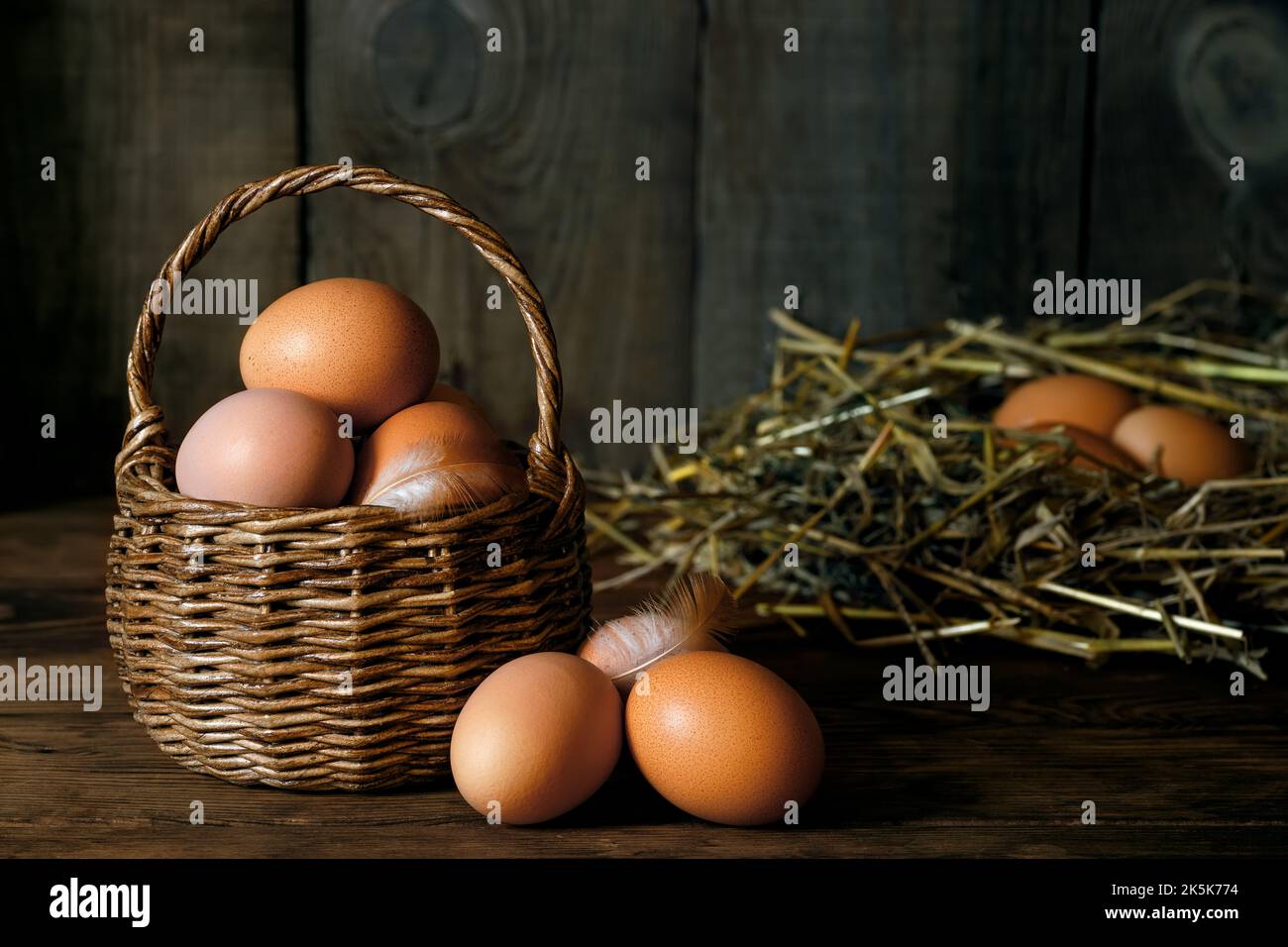 chicken eggs in wicker basket and in nest Stock Photo