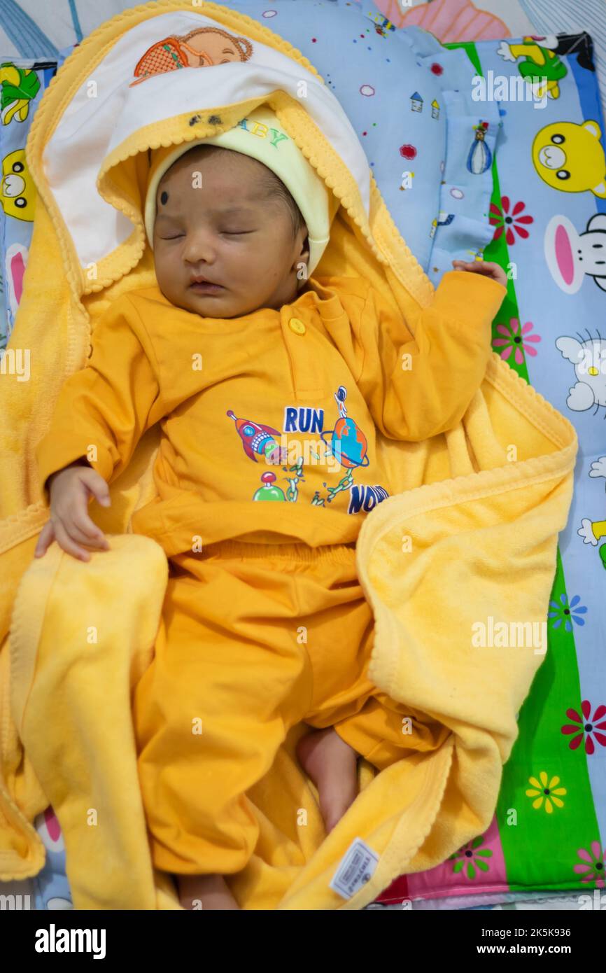 cute newborn baby sleeping in yellow dress from top angle Stock Photo
