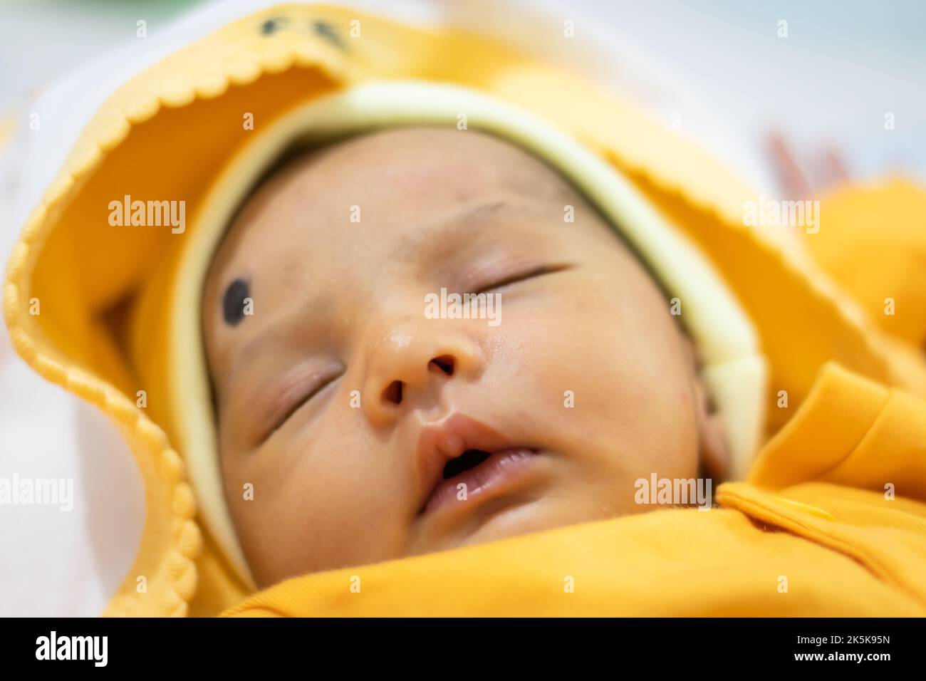 cute newborn baby sleeping in yellow dress from top angle Stock Photo