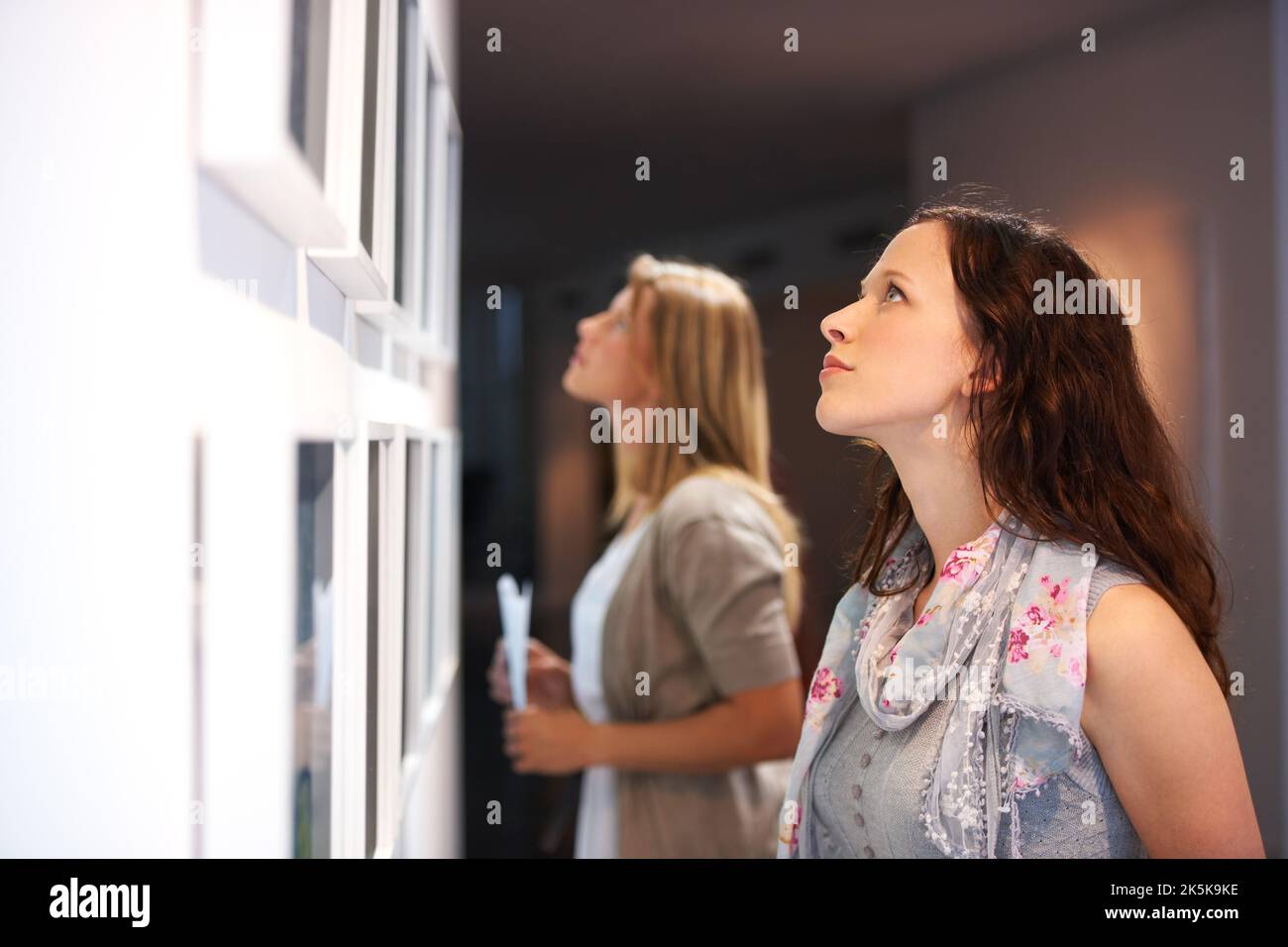 Closely examining the elements of a painting. Two female friends closely scrutinizing a painting at an exhibition. Stock Photo