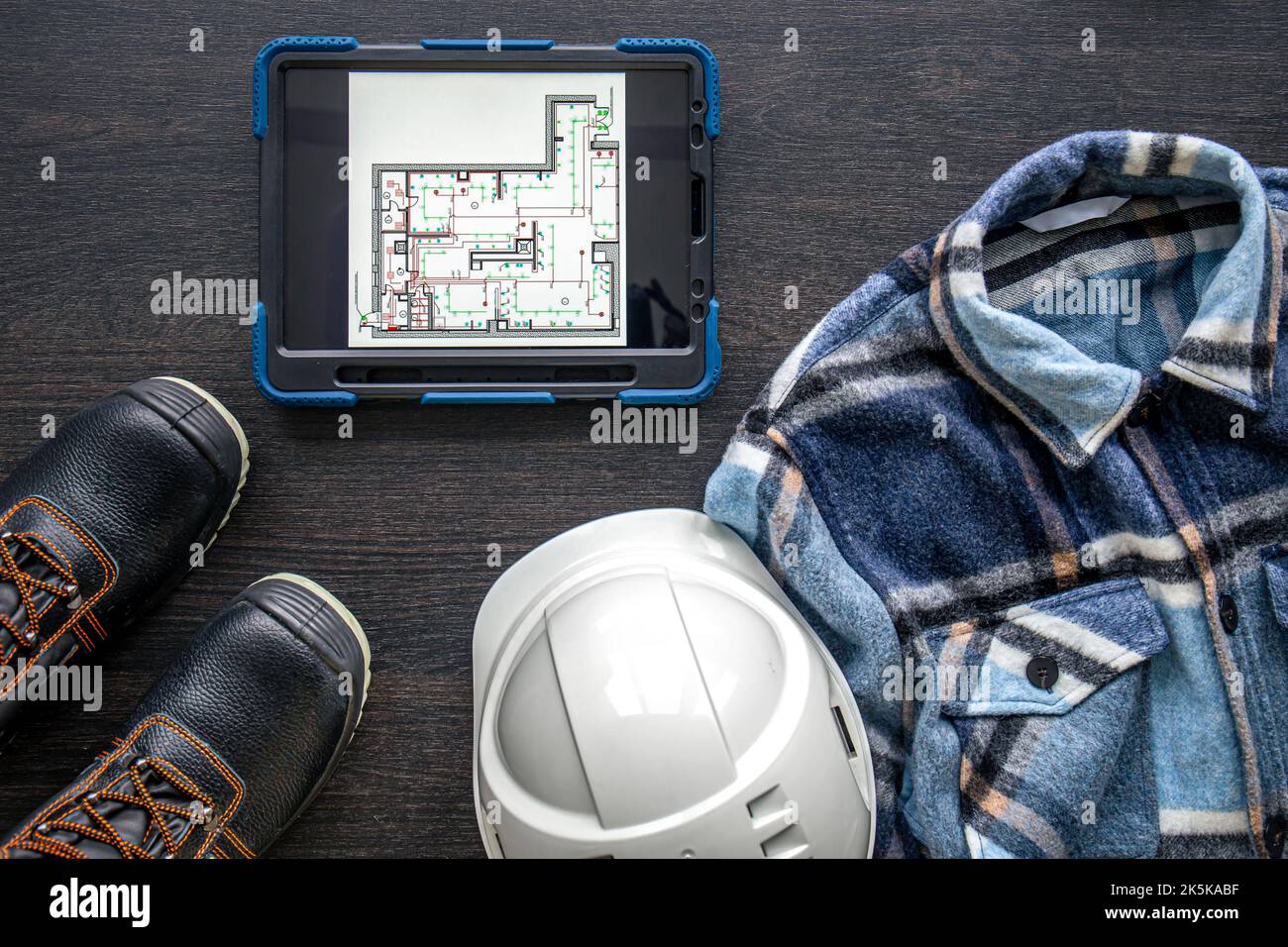 Digital tablet with layout and worker clothes, top view. Stock Photo