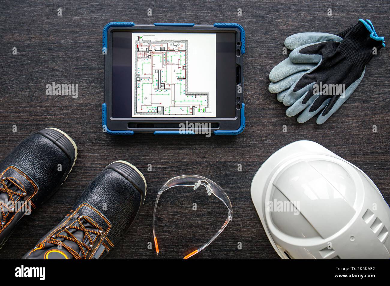 Digital tablet with layout and worker clothes, top view. Stock Photo