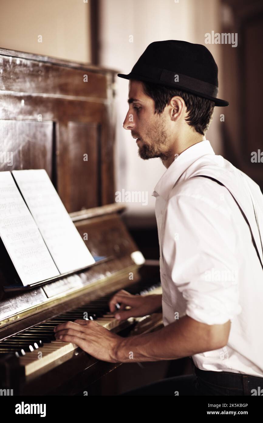 My bread and butter. A handsome young man playing the piano in a club. Stock Photo