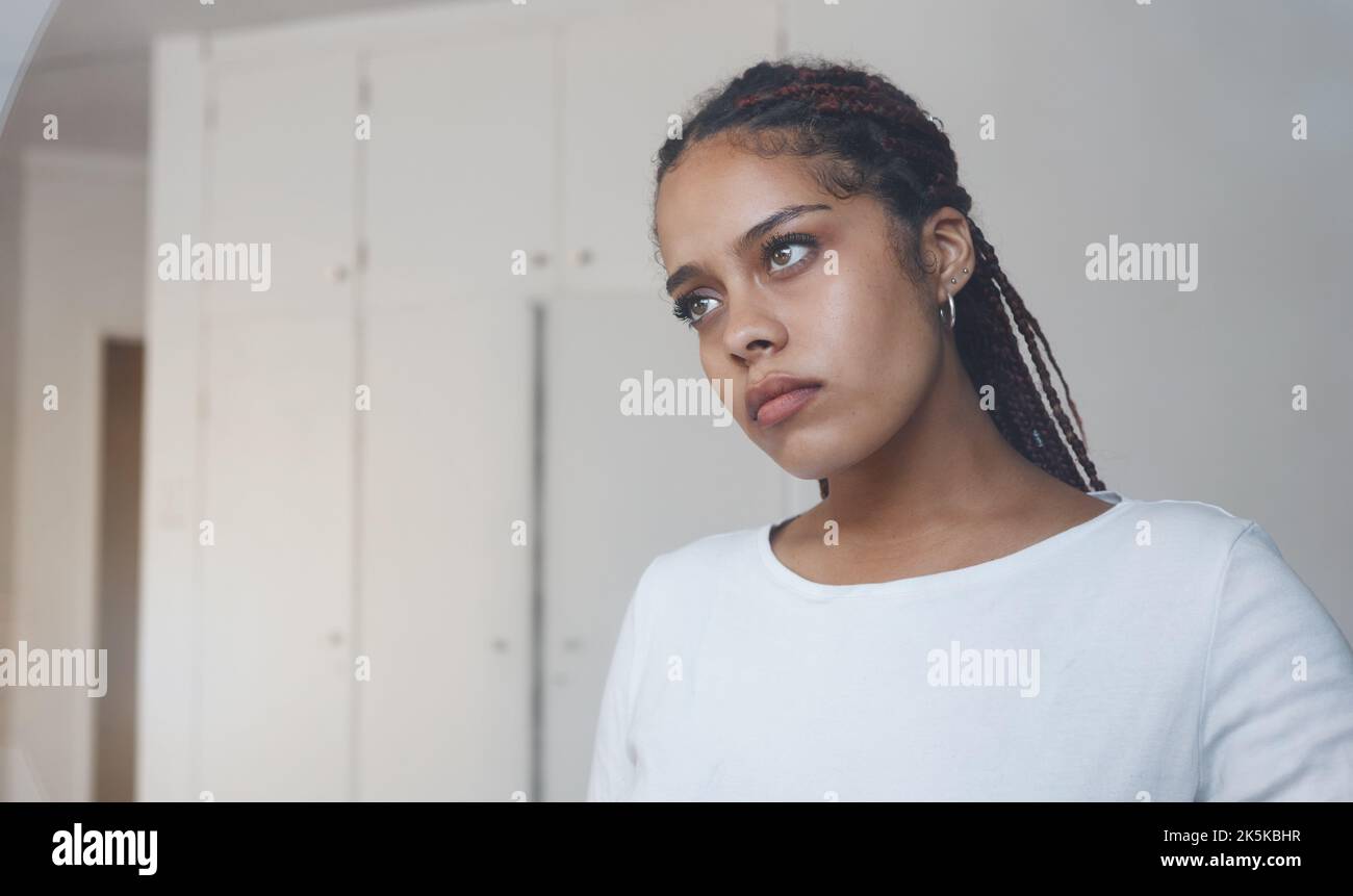 Sad, thoughtful and depressed woman in her home feeling alone and isolated. Mock up for depression, sadness and mental health issues. Thinking Stock Photo