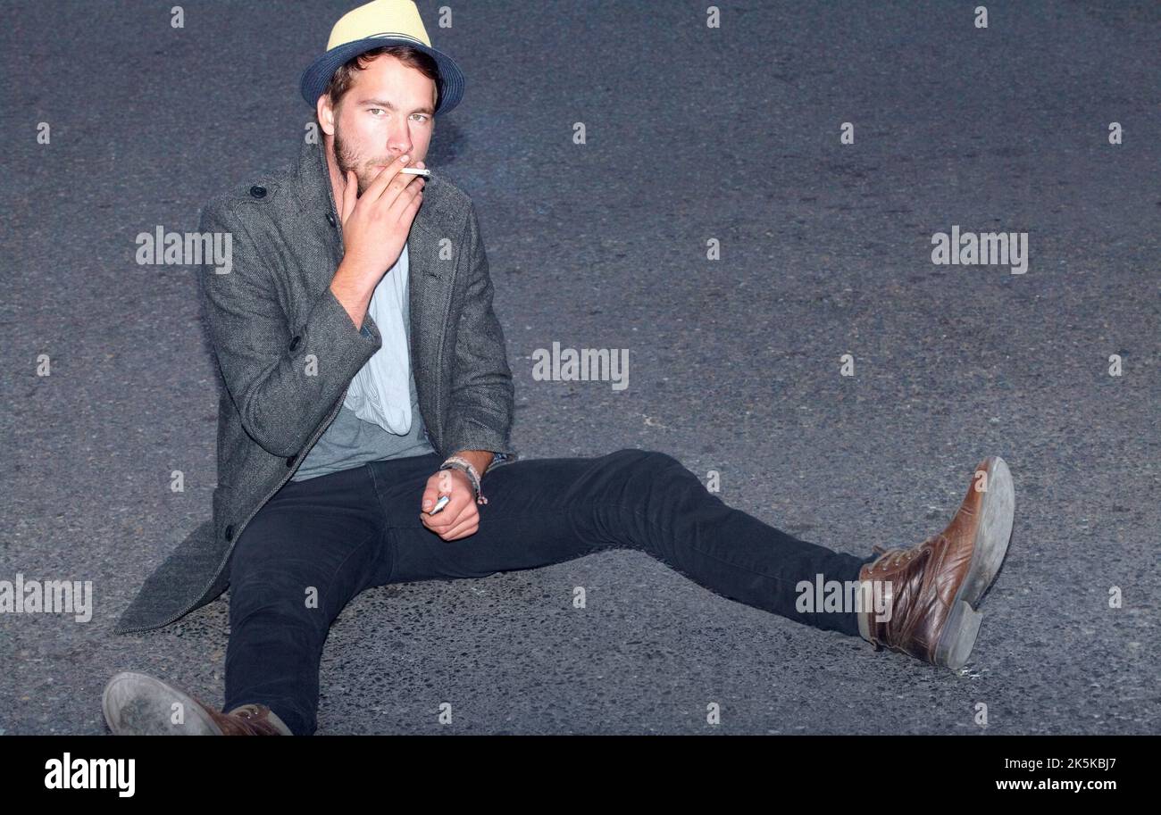 Hes hip and handsome. a handsome hipster sitting outside on the street. Stock Photo