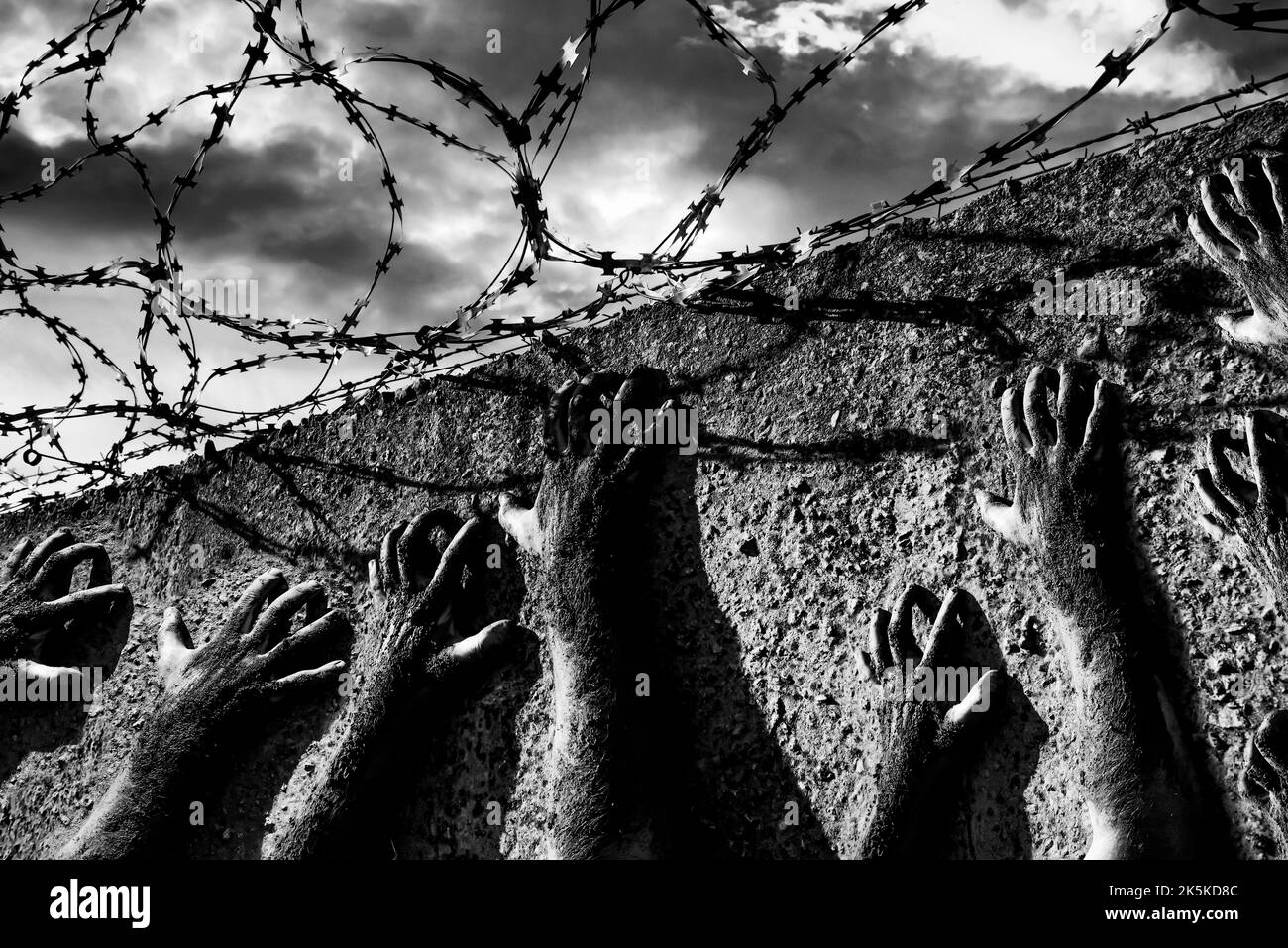 Jail break. Hands holding on to barbed wire on the wall of the prison