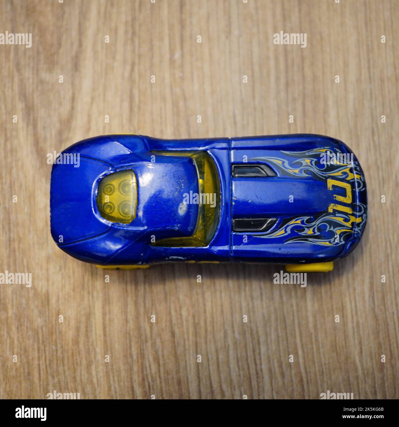 The top view of a blue Mattel Hot Wheels toy car on a wooden surface