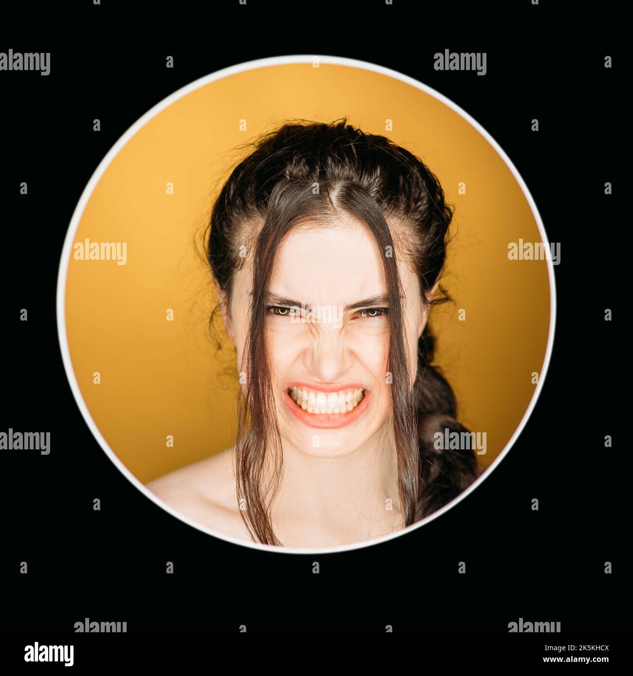 Angry woman. Anxiety frustration. Emotional crisis. Nervous breakdown. Headshot portrait of furious annoyed mad girl face isolated on orange in circle Stock Photo