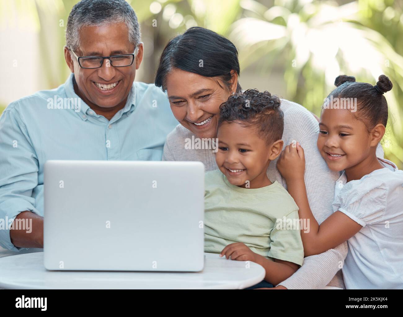 Grandparents, children and laptop on video call with family in house
