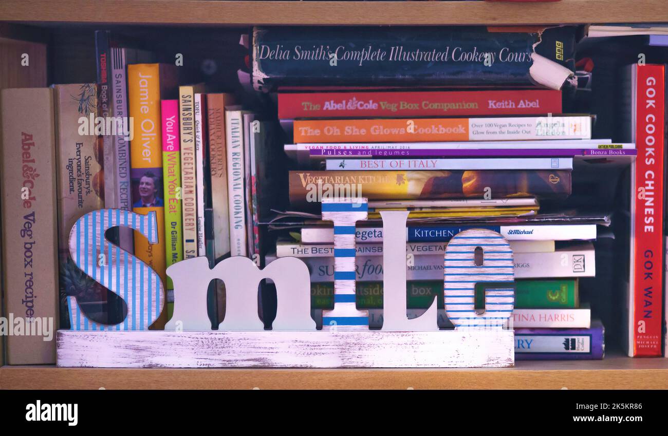 A shelf on a bookcase holding cookery books behind a bookend saying ...
