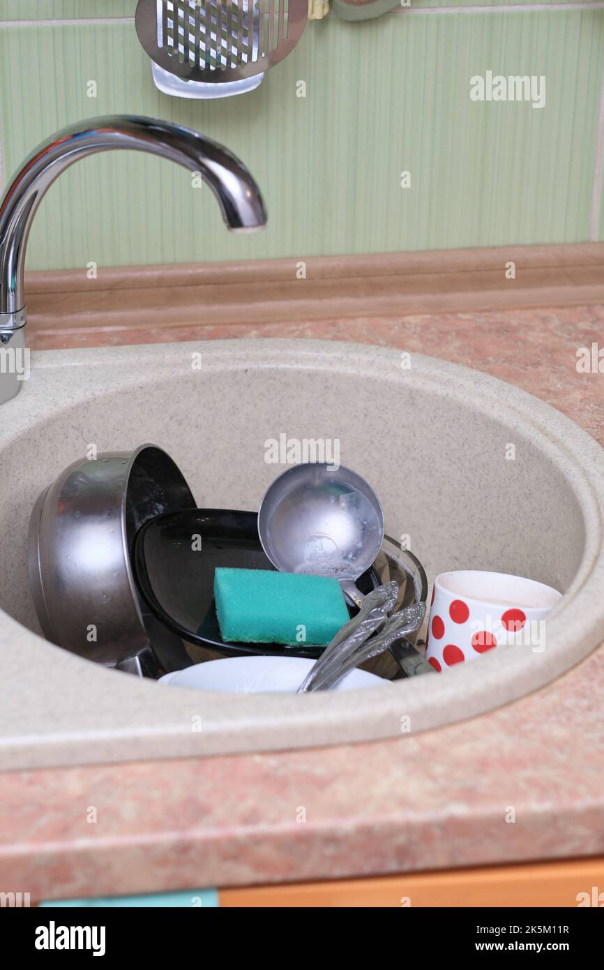 dirty dishes and kitchen utensils in a sink. messy kitchen. cluttered