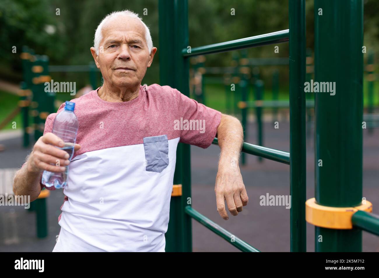 Senior man with bottle of water in sports ground Stock Photo - Alamy