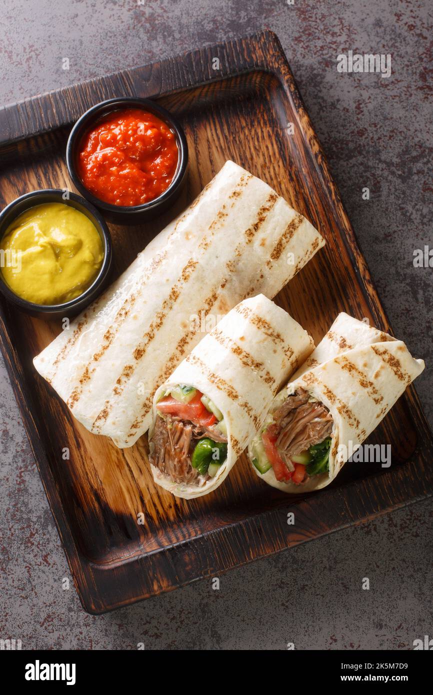 durum doner lavash shaurma meat closeup on the wooden board on the table. Vertical top view from above Stock Photo