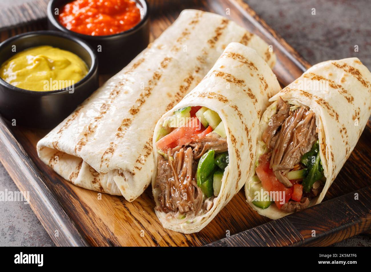 Doner kebab or shawarma with beef and fresh vegetables closeup on the wooden board on the table. Horizontal Stock Photo