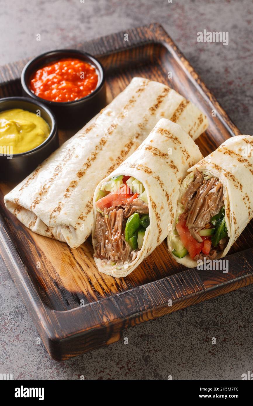 durum doner lavash shaurma meat closeup on the wooden board on the table. Vertical Stock Photo