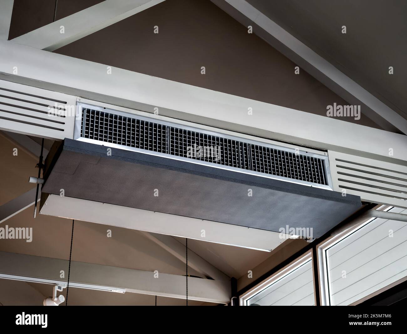 Air conditioning wall mounted ventilation system on ceiling in the white hotel room. Hotel room