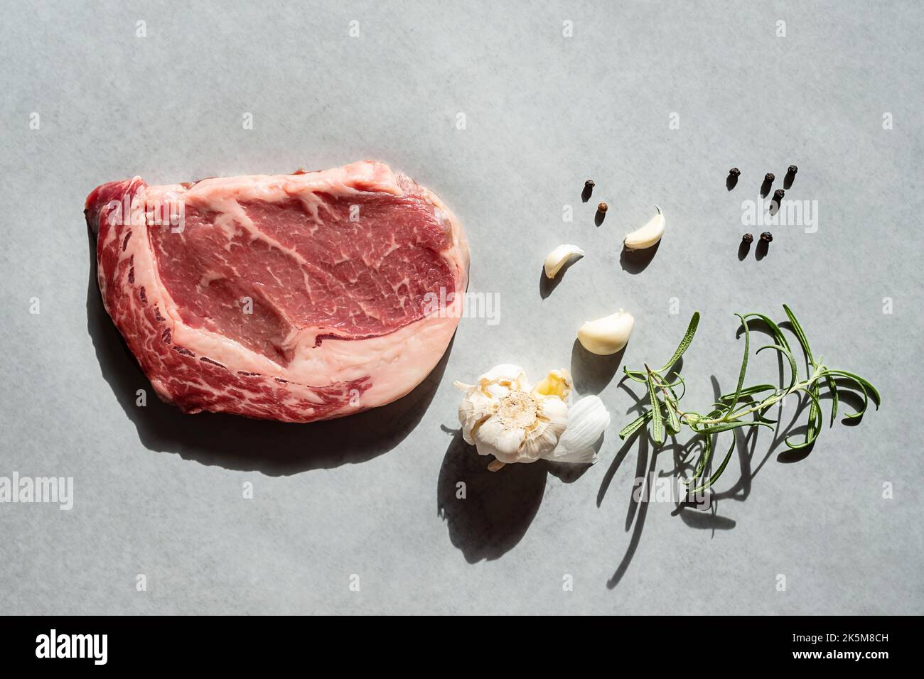 Raw ribeye steak with rosemary garlic and pepper ready to cook Stock ...