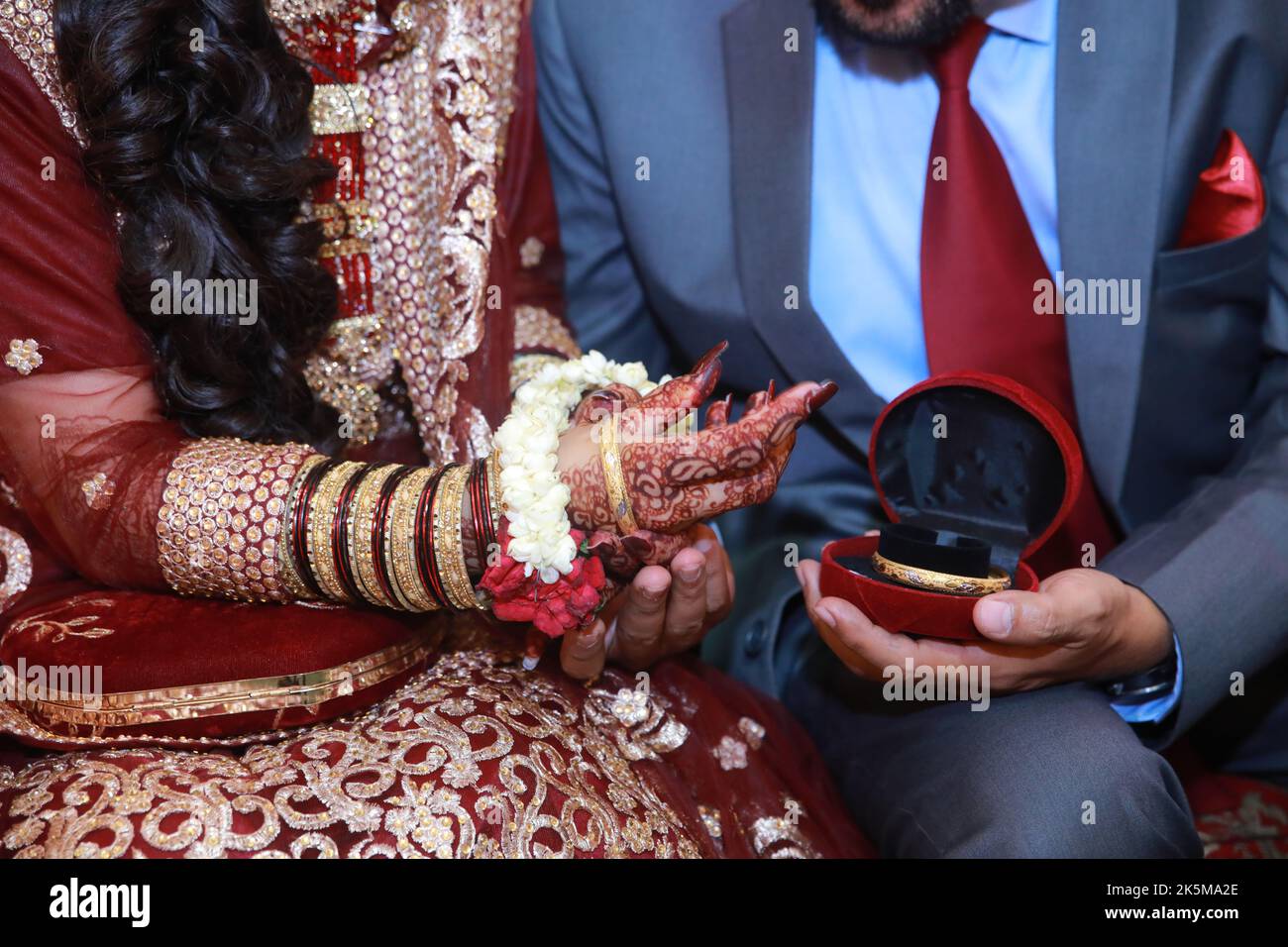 Groom presenting gift of gold bangles to bride Stock Photo