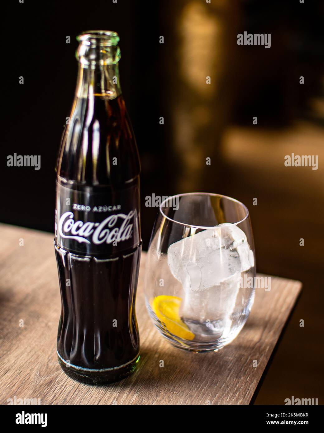 A big coke in a wood table with a glass with ice and a lemon inside. Pub time Stock Photo