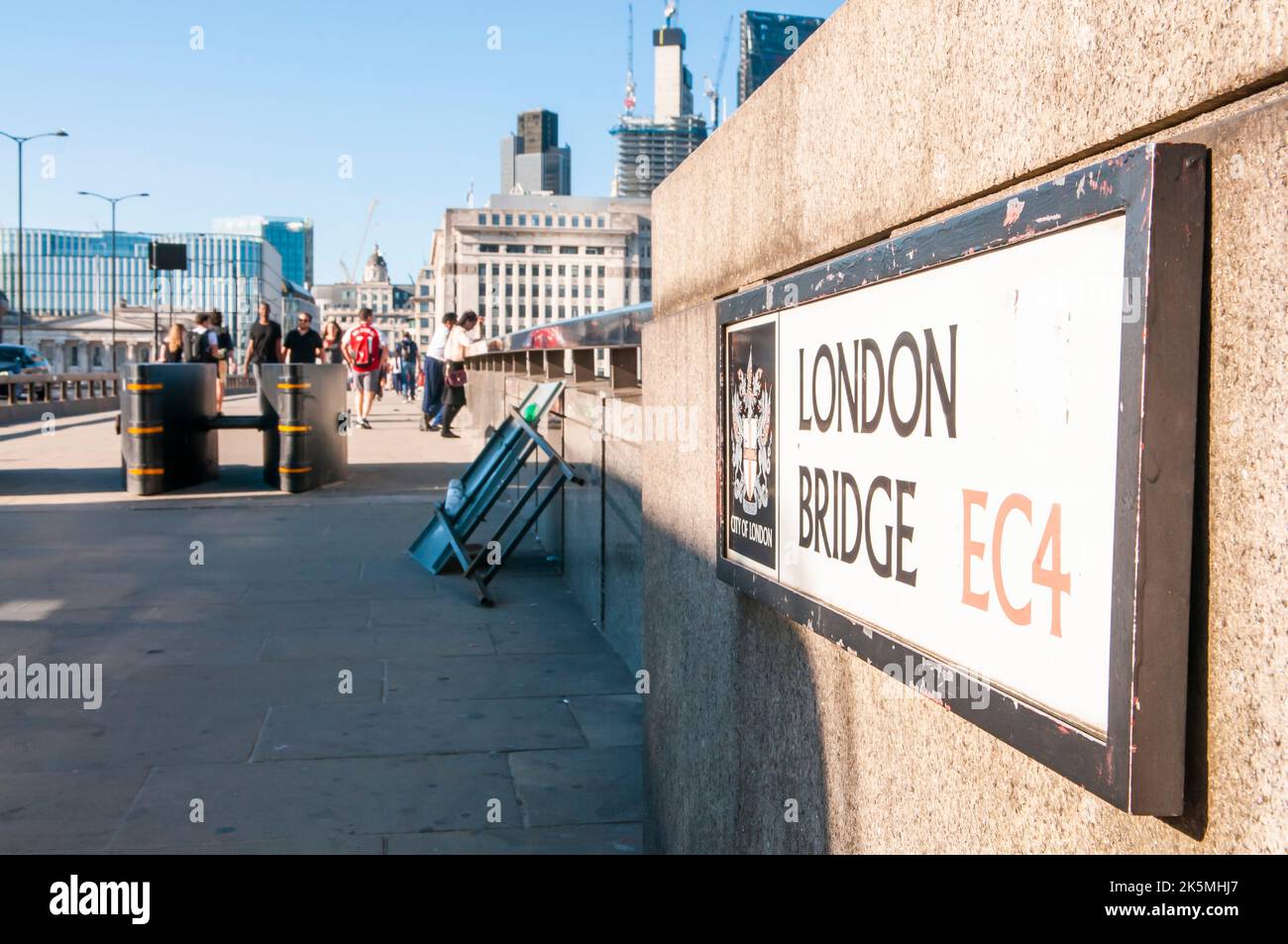 Sign for London Bridge with anti-terrorist barriers behind following a terror attack in 2017 when a van was deliberately driven at pedestrians on the footpath, killing 8 and wounding 48, London, England. Stock Photo