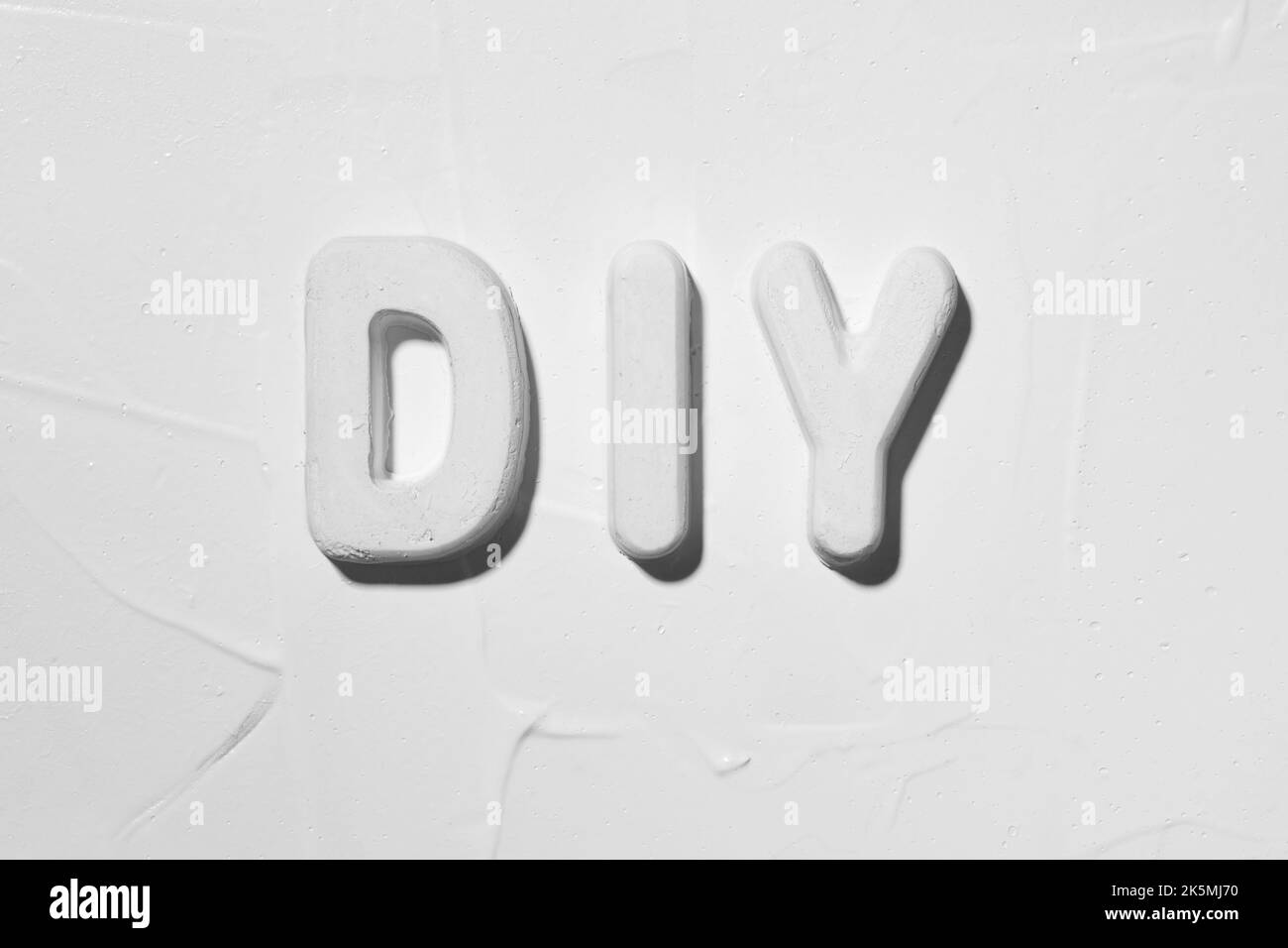 DIY (Do It Yourself). Plaster moulded letters on white stucco Stock Photo