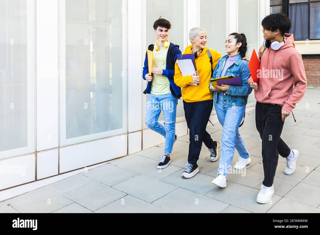 Happy young group of diverse student friends walking at college campus Stock Photo