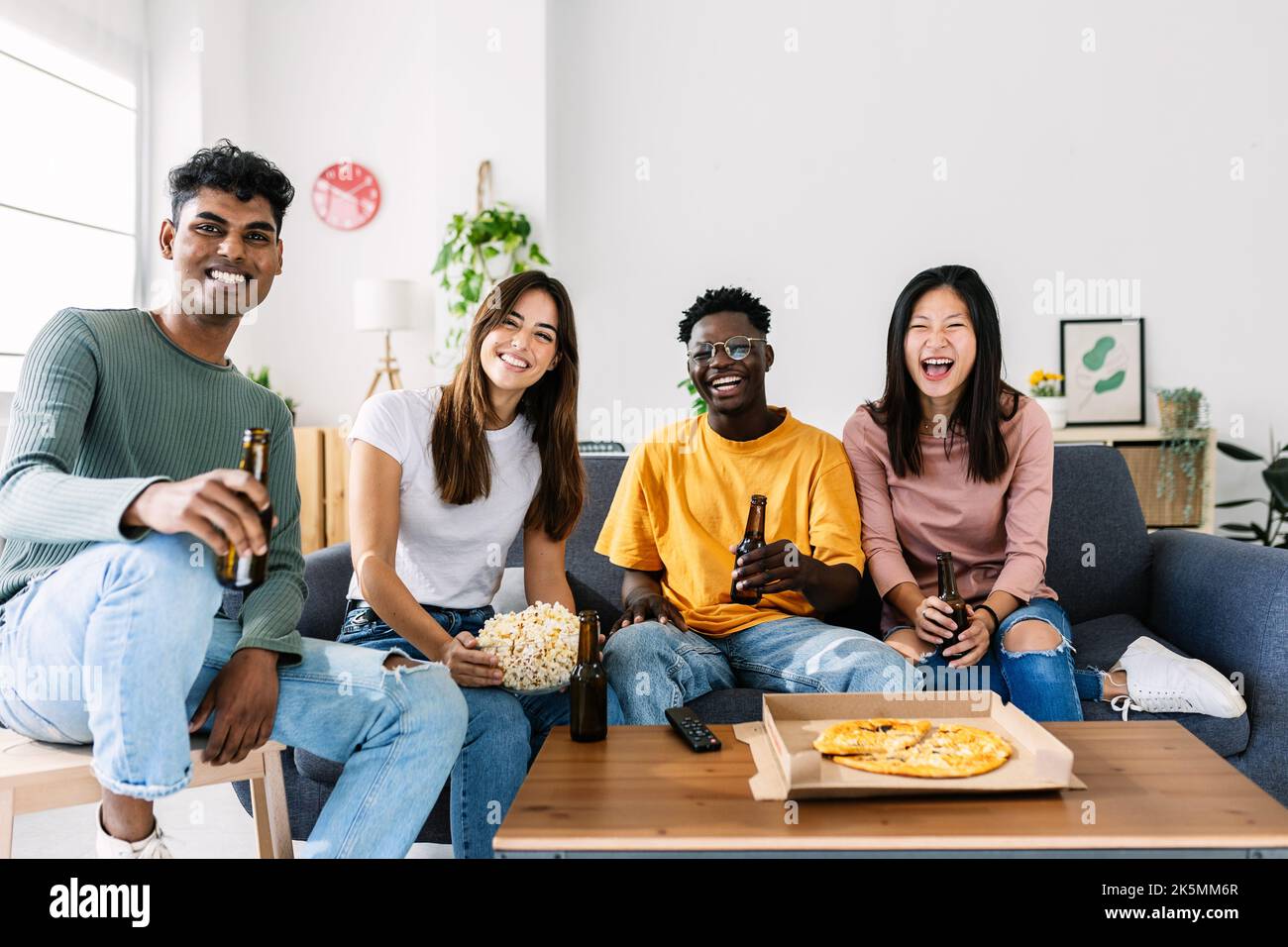 Multiethnic happy friends watching TV at home Stock Photo