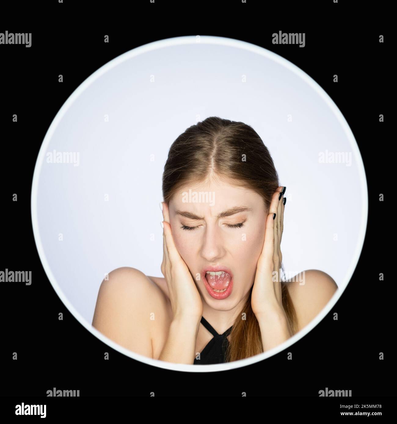Frustrated woman face. Anxiety attack. Nervous breakdown. Headshot portrait of disturbed annoyed girl yelling covering ears isolated on light in circl Stock Photo