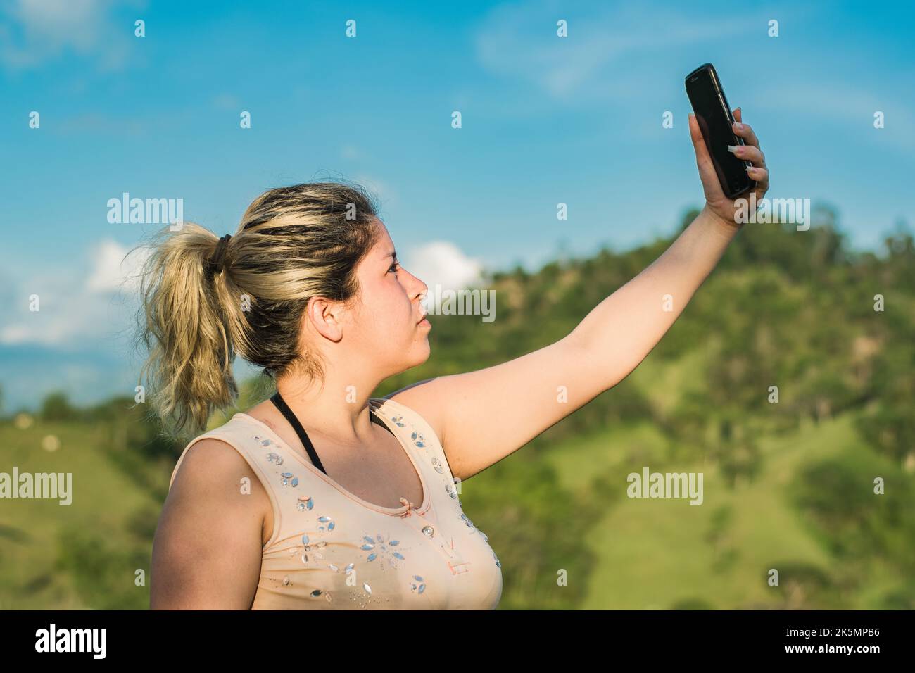 beautiful young latin woman on top of a colombian mountain raising 