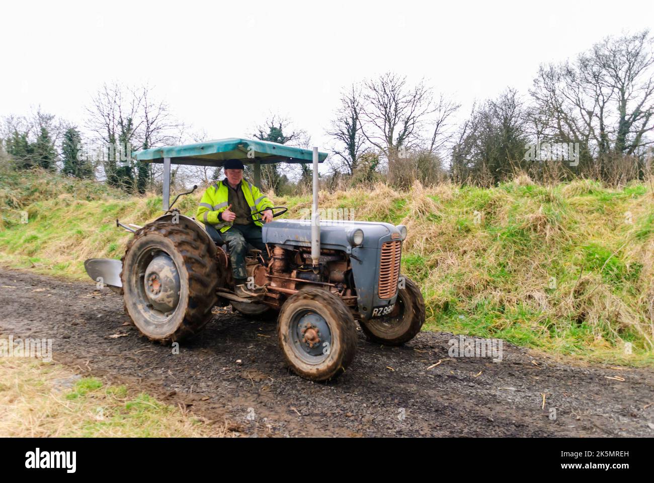 A farmer gives a thumbs up gesture as he drives a Fordson tractor along