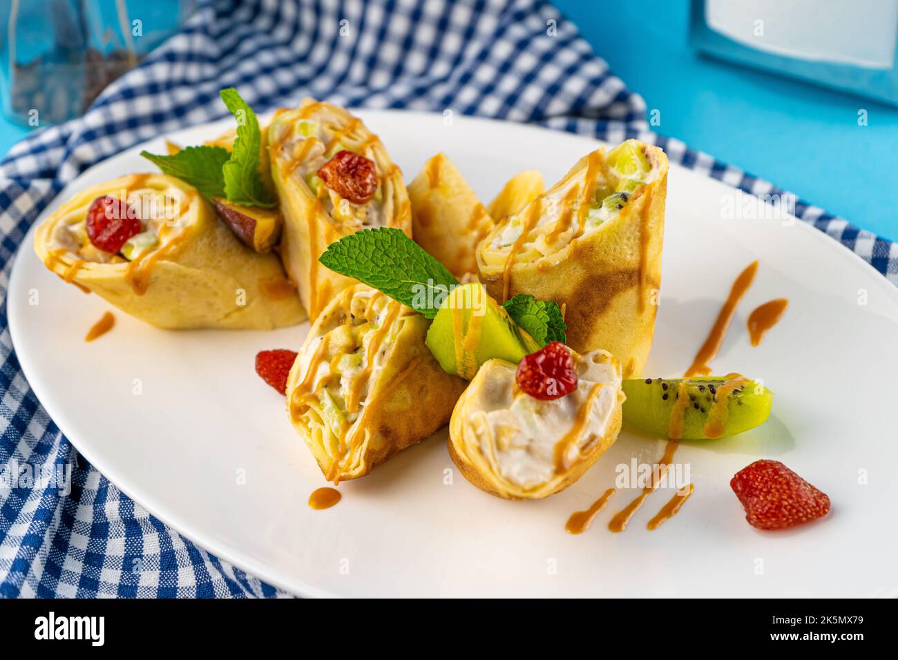 Simple homemade pancakes cut with banana kiwi strawberry jam on a