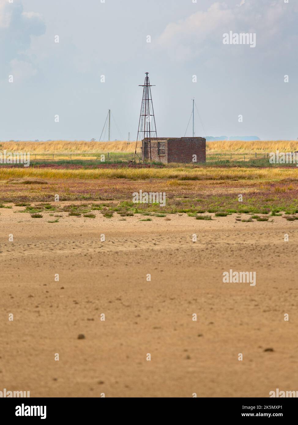 Remnants of hut and mast in a grass and salt marsh landscape, airfield area, Orford Ness, Suffolk, England Stock Photo