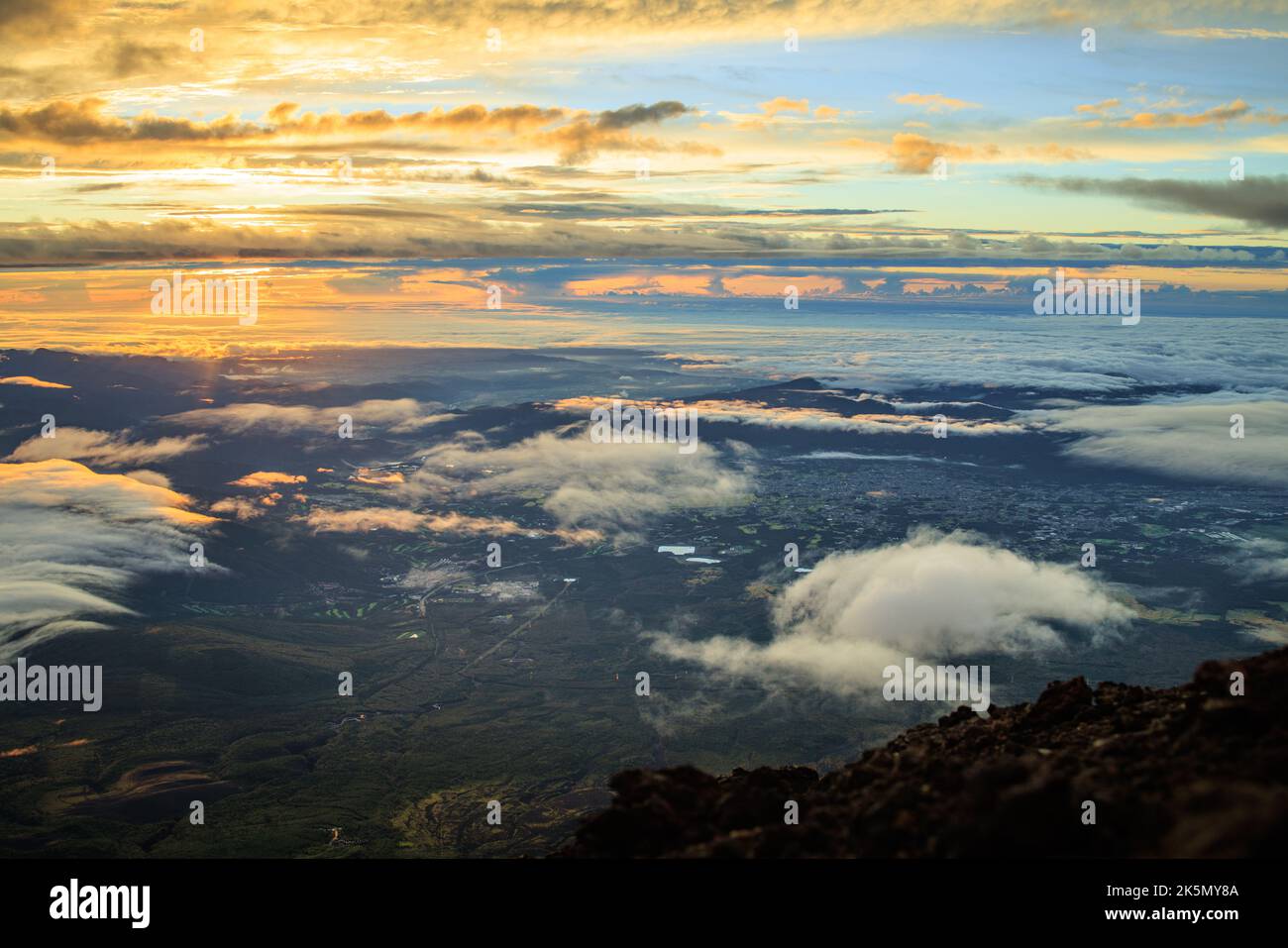 Mountaintop view of early morning sun behind clouds and expansive landscape Stock Photo