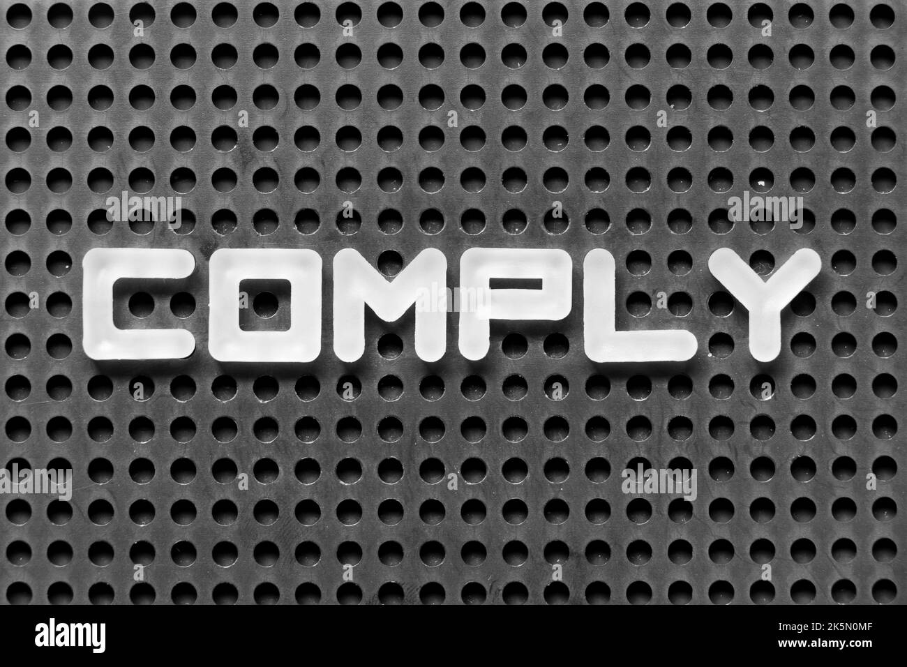 White alphabet letter in word comply on black pegboard background Stock ...