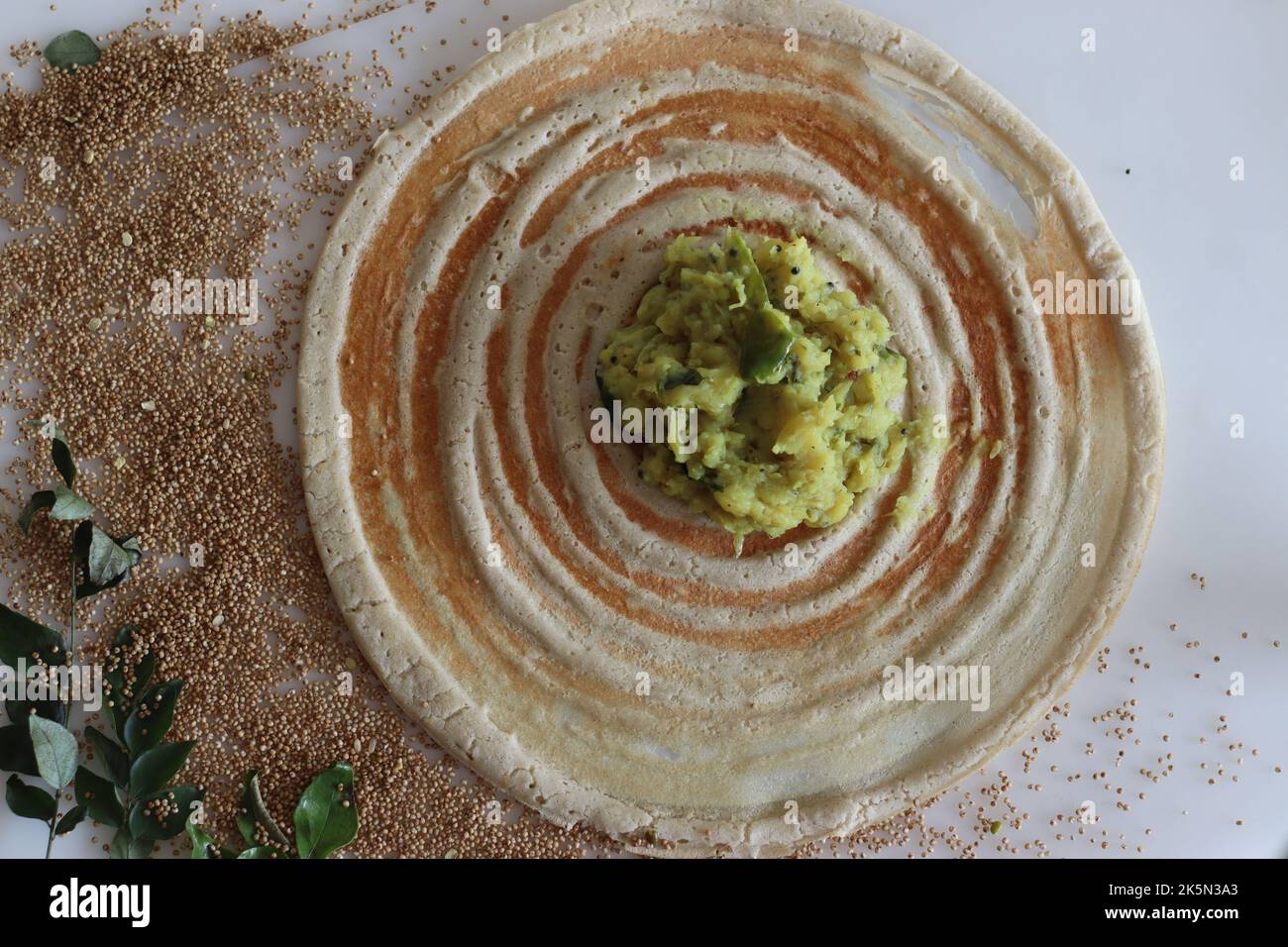 Kodo millet masala dosa. Thin crispy crepes made of kodo millet and lentils flour, stuffed with spiced mashed potatoes. Shot on white background. Stock Photo
