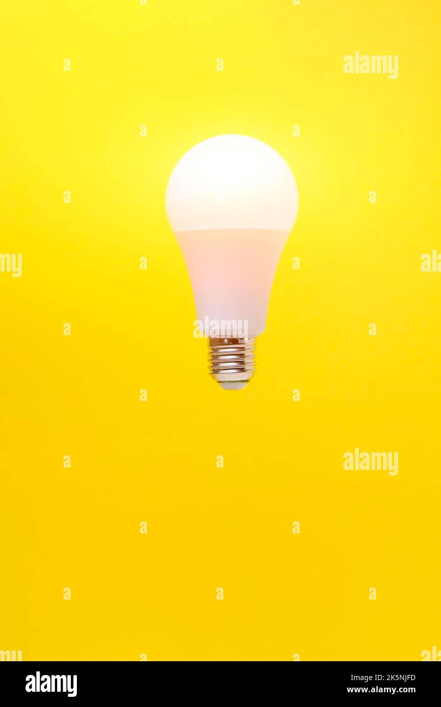 Burning LED eco friendly light bulb on yellow background Stock Photo