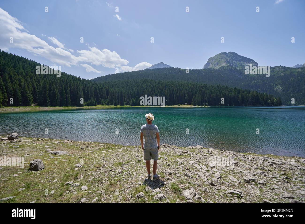Tourist enjoys nature and life, looking at the lake and mountains. Stock Photo