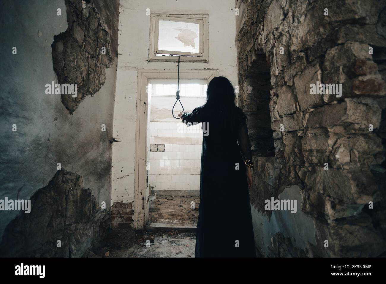 Ghost in abandoned, haunted house. Horror scene of scary spirit of a woman and rope with a noose, halloween concept. Stock Photo