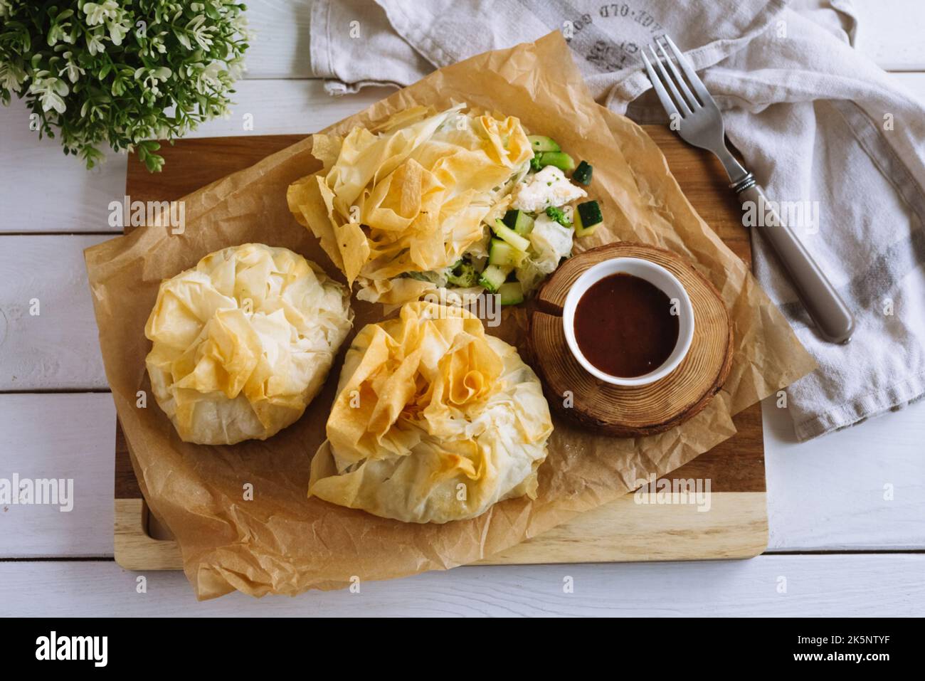 Phyllo Purses. Filo dough filled with chicken and vegetables on parchment paper with barbecue sauce. Three baked filled veggie pastry bags. Mixed Vege Stock Photo