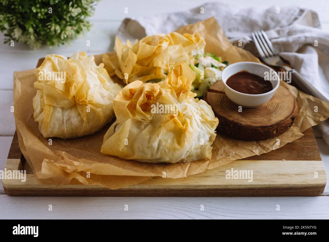 Phyllo Purses. Filo dough filled with chicken and vegetables on parchment paper with barbecue sauce. Three baked filled veggie pastry bags. Mixed Vege Stock Photo