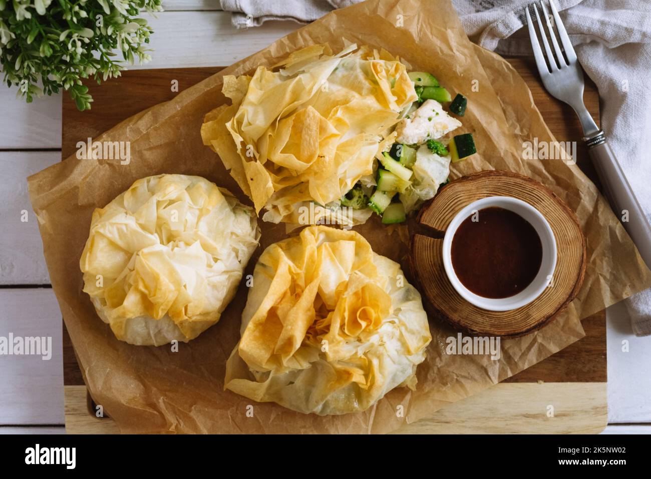 Phyllo Purses. Filo dough filled with chicken and vegetables on parchment paper with barbecue sauce. Three baked filled veggie pastry bags. Mixed Vege Stock Photo