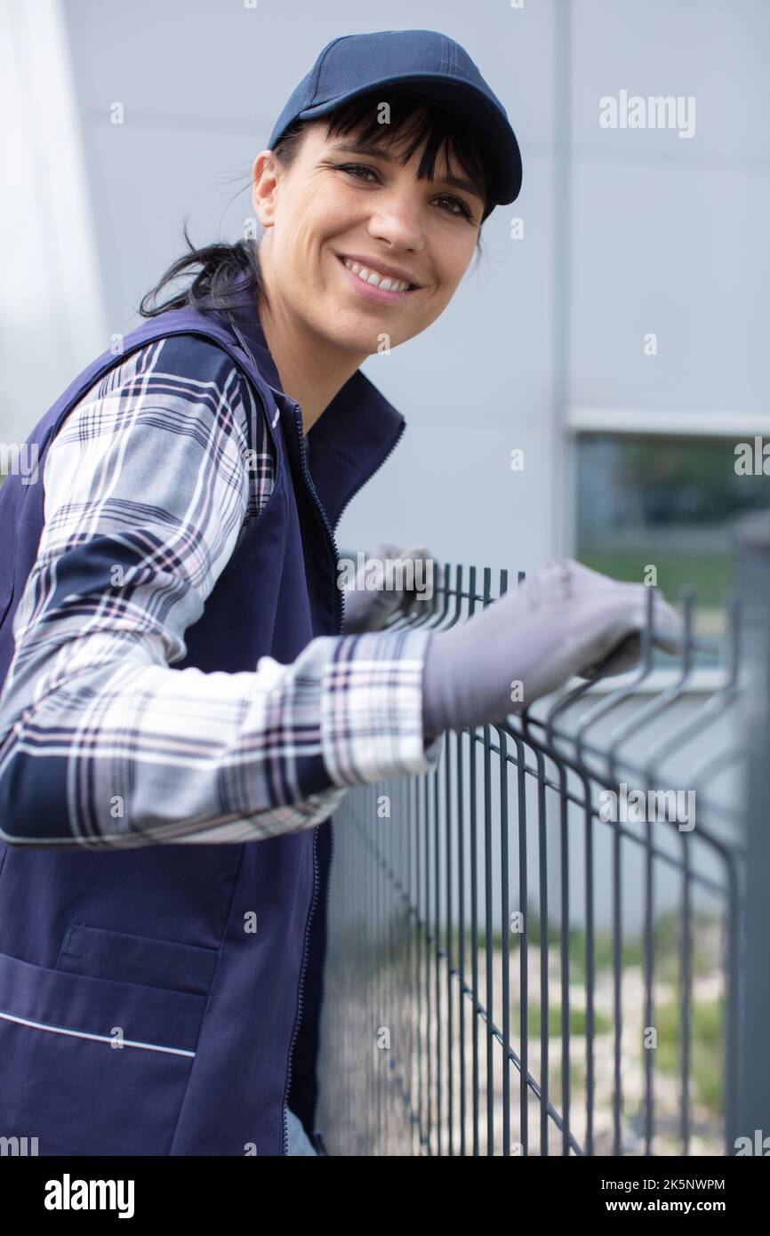 worker installing welded metal mesh fence Stock Photo