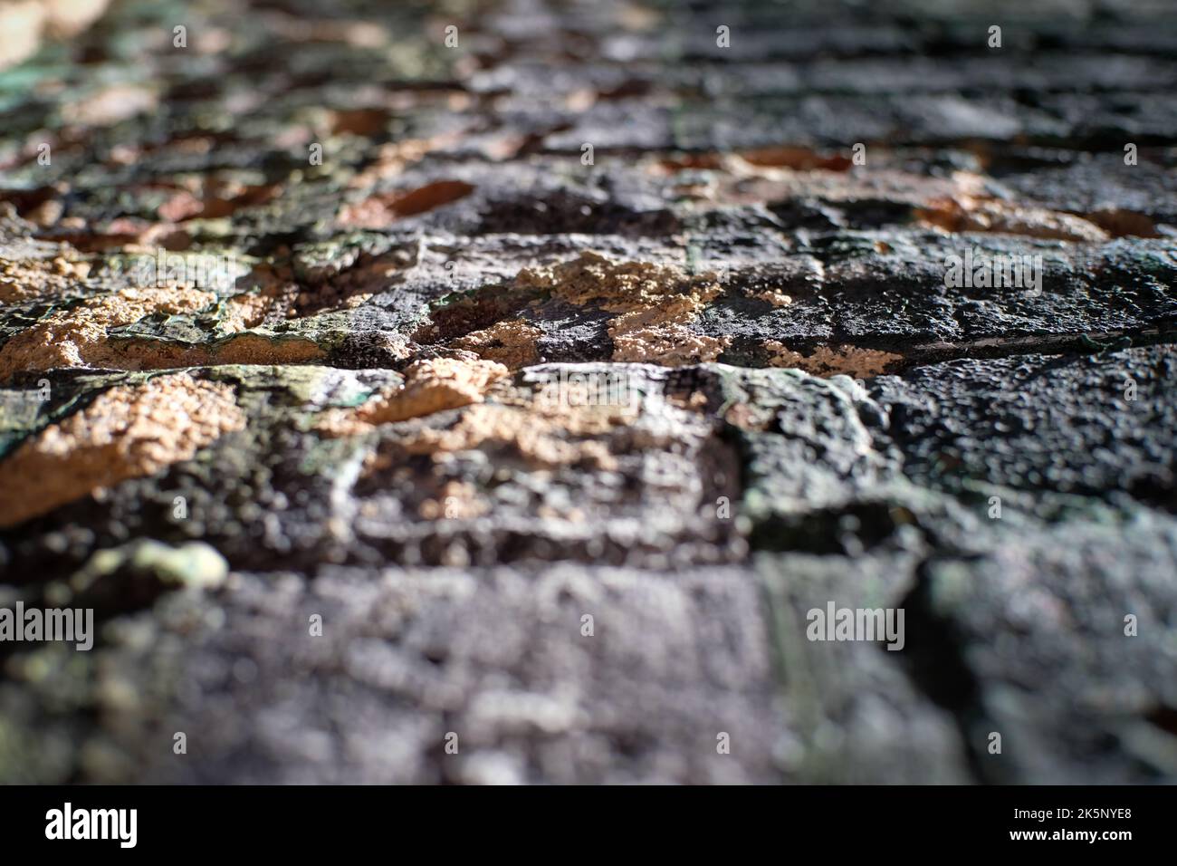 Worn brick wall with flaking and peeling paint from low perspective