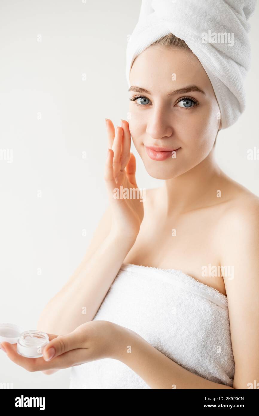 Wrinkle prevention. Beautiful woman. Facial cosmetic. Anti-aged treatment. Pretty lady applying face cream isolated white. Stock Photo