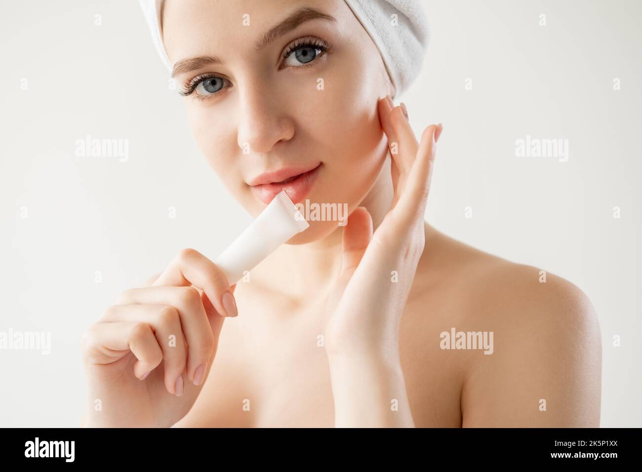 Facial beauty. Pretty woman. Anti-aged rejuvenation. Moisturizing treatment. Smiling lady posing with face cream tube isolated white. Stock Photo
