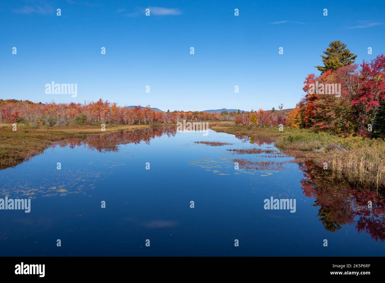 fall foliage and blue skies reflecting on the outlet from Sacandaga