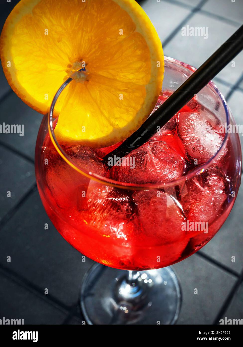 Summer cocktail, red italian alcoholic beverage, drink with ice, sliced orange and straw, closeup. Stock Photo